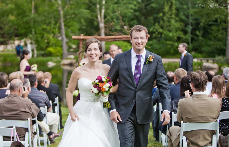 Cute couple walk down the aisle at their outdoor wedding ceremony at the Yampa River Botanic Park