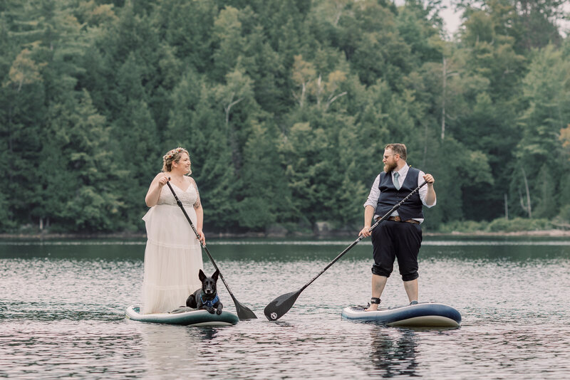 On a dirt path in Keene Valley with the Adirondack mountains behind them, a bride and groom are holding hands and walking together after their ceremony during their elopement.