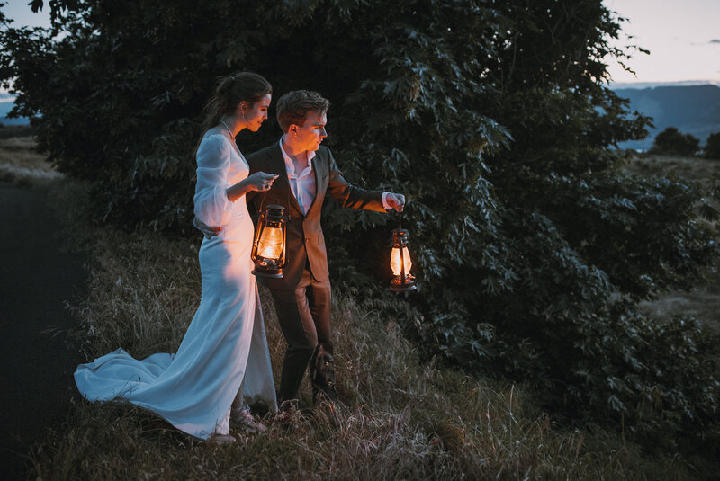 Bride and groom holding lanterns in the dusk