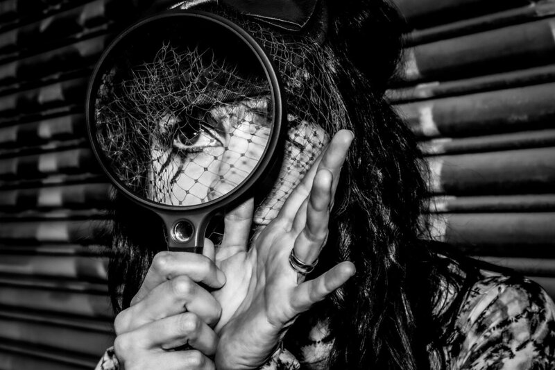 Female musician portrait Los Angeles music artist Vanderocker closeup looking through magnifying glass black and white