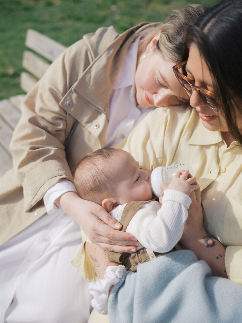 Mother and son sharing a cuddle while smiling seated on a blanket at a park 
