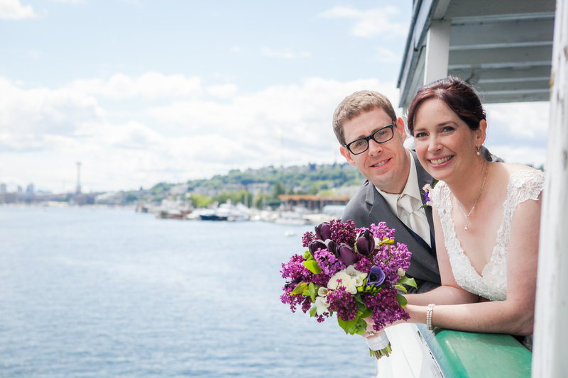 bride and groom pose on a boat in seattle
