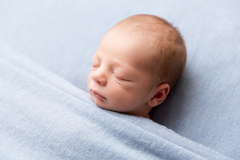 baby boy tucked into blue blanket