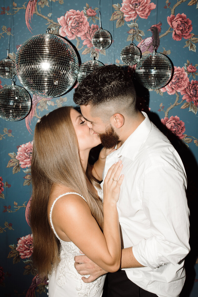 man & woman standing under lights kissing
