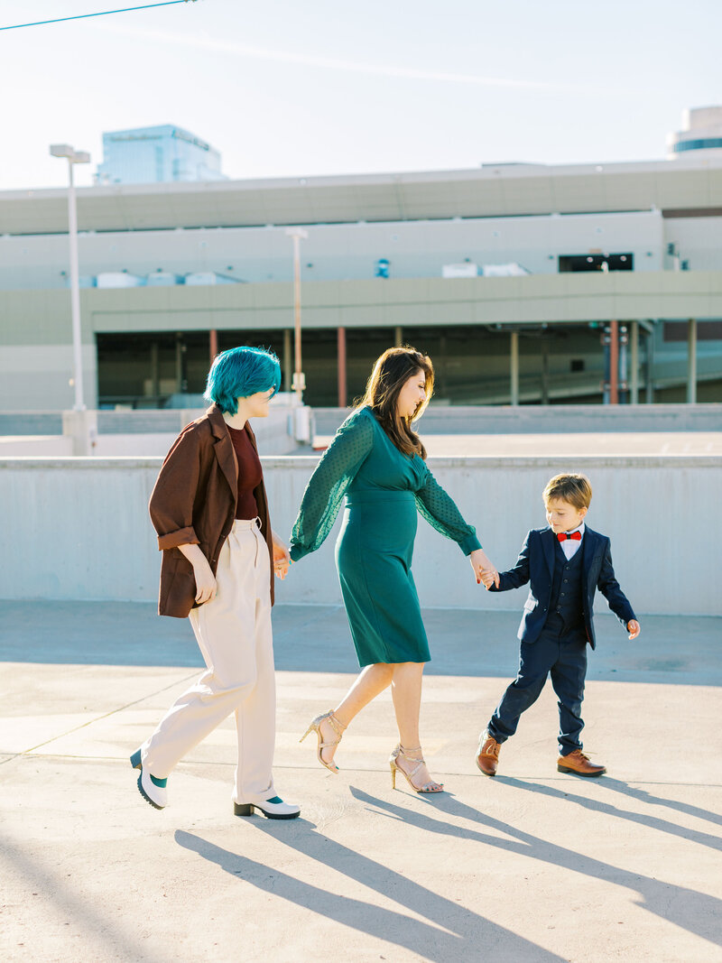 family of three holding hands and walking