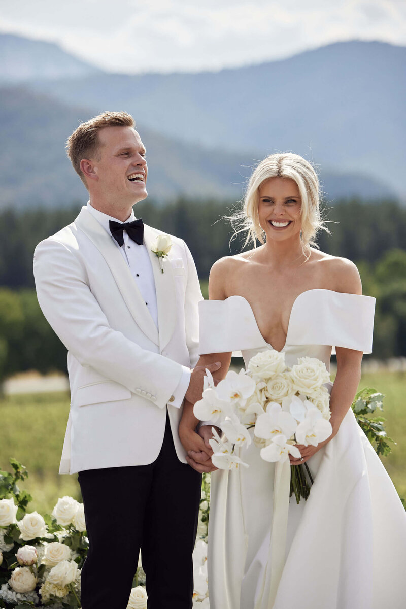 Bride and groom at ceremony on white stage under trees