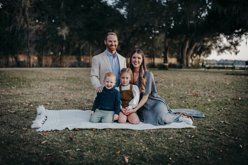 family with two adults and  two young kids on a picnic blanketfor old town bluffton family session