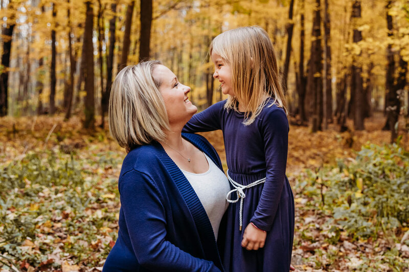 mom and daughter laughing with each other during fall for family photography session