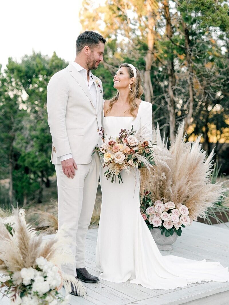 Newlyweds posing with dried pampas grass and blush bouquet designed by Austin wedding florist Flora Fetish.