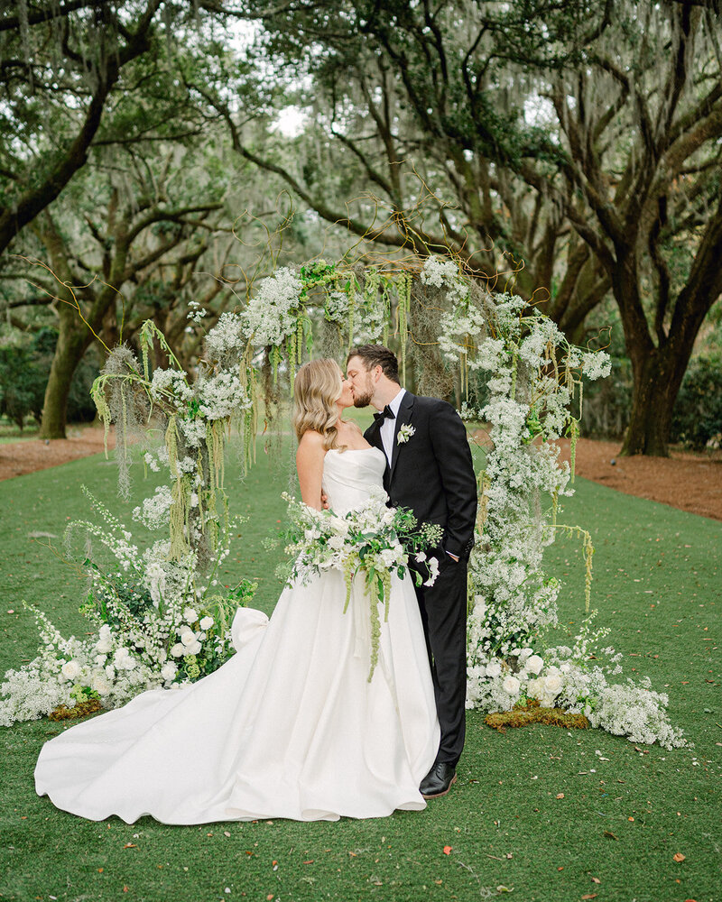 Bride and Groom share a kiss at their wedding arbor at Legare Waring House in Charleston, South Carolina.
