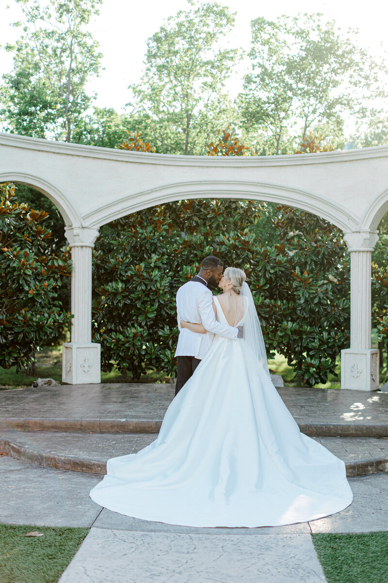 Swank Soiree Dallas Wedding Planner Kelci and CJ Knotting Hill Place - Bride and Groom kissing in a garden