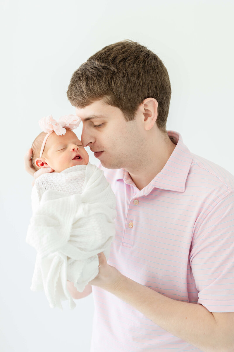 Dad snuggling newborn baby for newborn photography session in dothan alabama photography studio