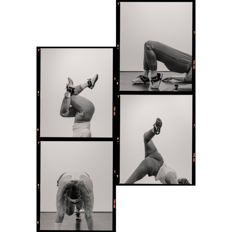 Black and white image of Alex Paige in a yoga pose with arms overhead and one knee bent