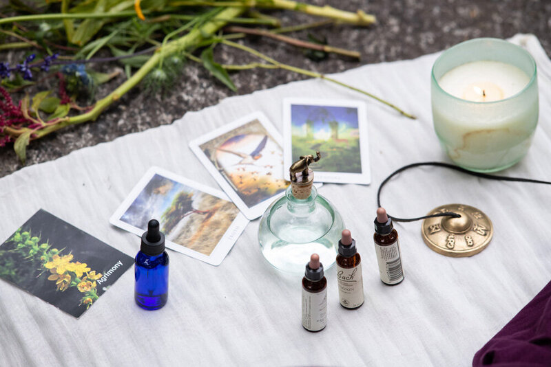 flower essences and oracle cards on a white blanket