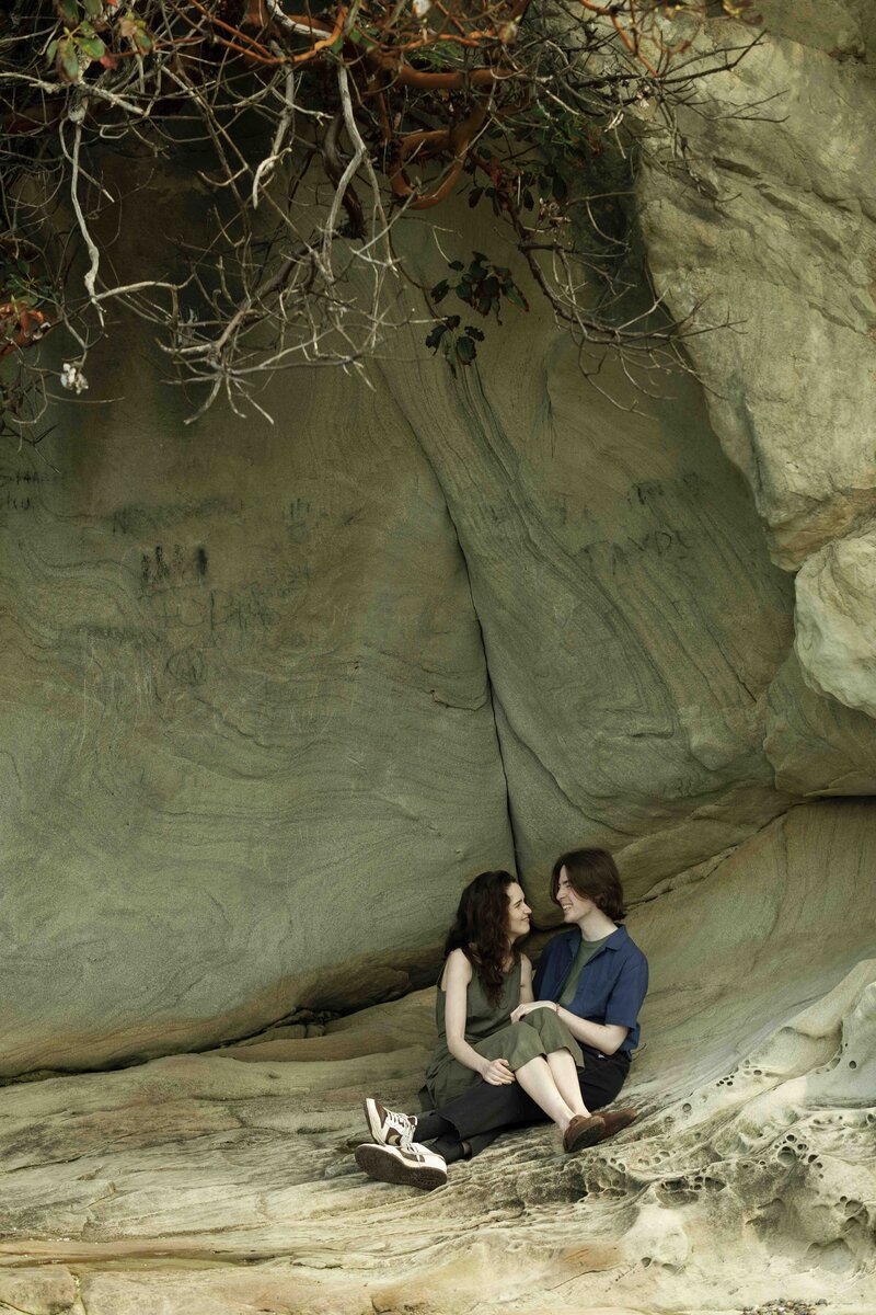 Couple sitting in an alcove on the beach at Larrabee State Park during engagement