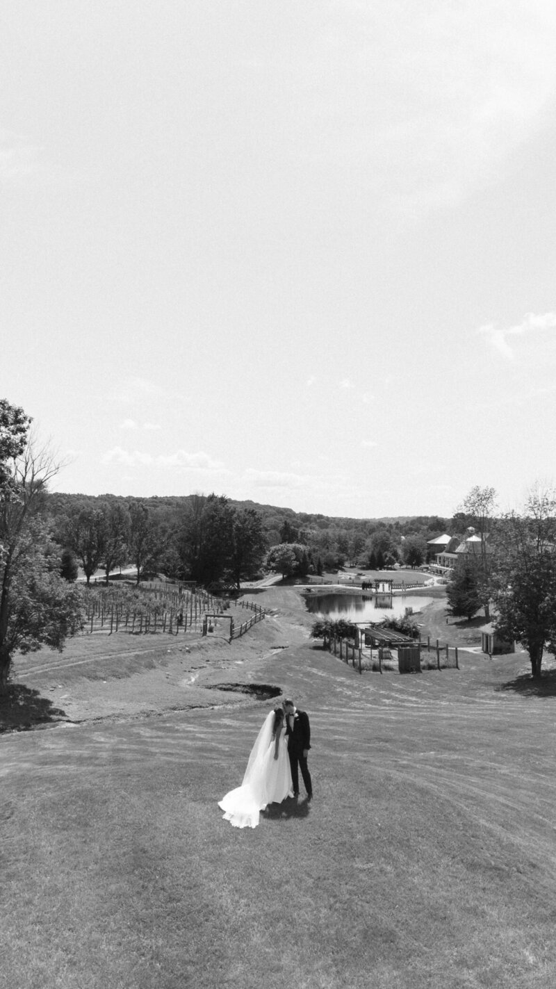 Anya and George on the lawn above the vineyard and pond, in black and white