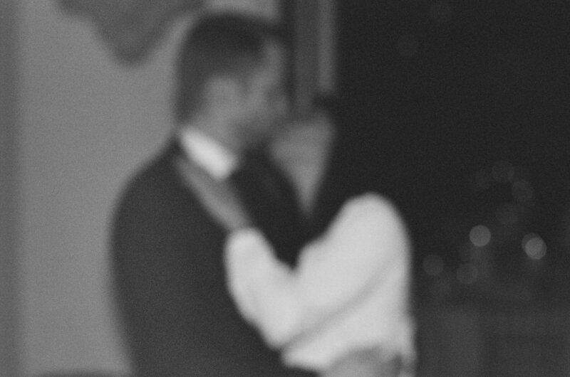 blury black and white photo of bride and groom kissing
