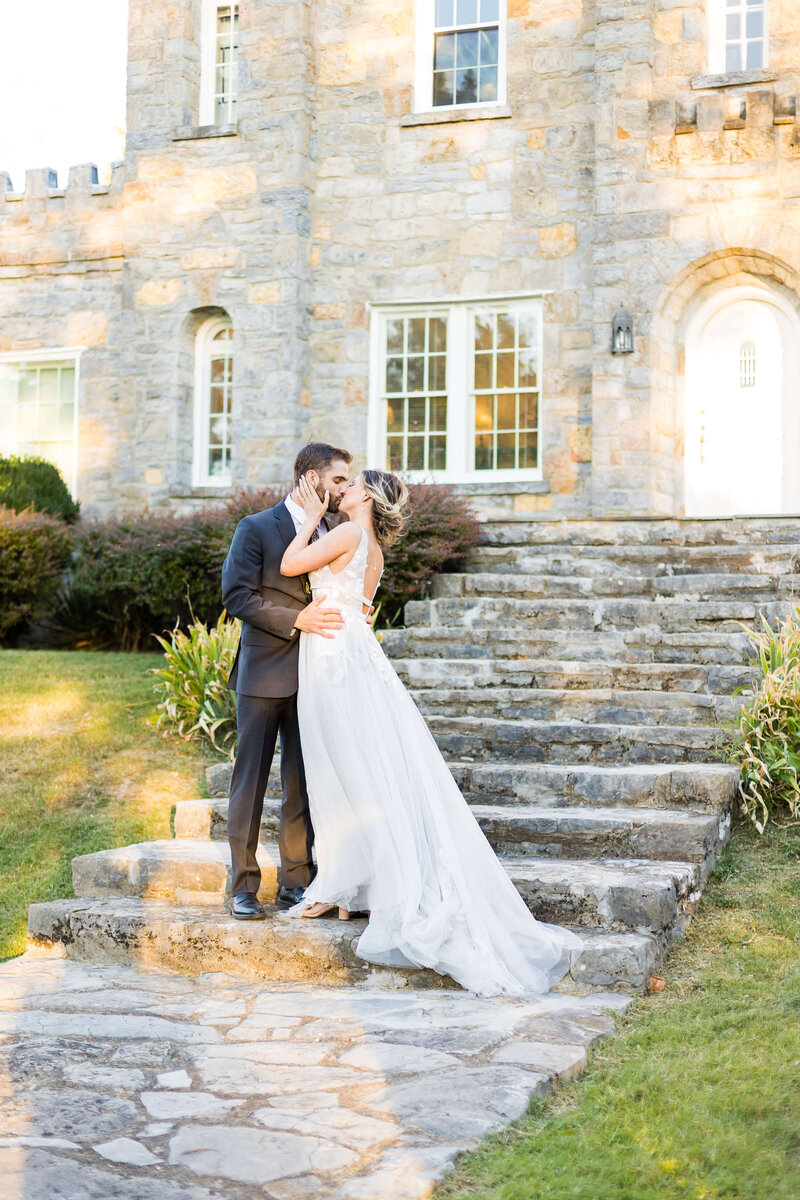 Bride and groom kissing on stone steps in front of a old building