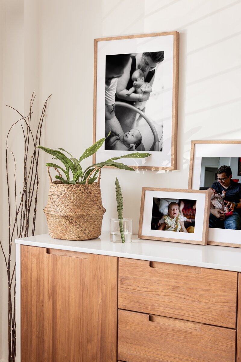 a wall with three framed newborn pictures