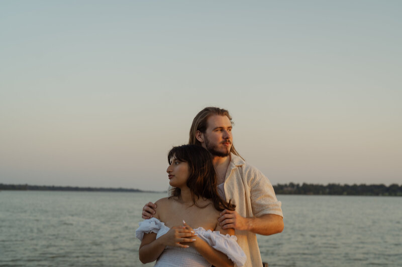 An intimate couples portrait taken at White Rock Lake in Dallas, featuring a couple embracing amidst a serene park background.