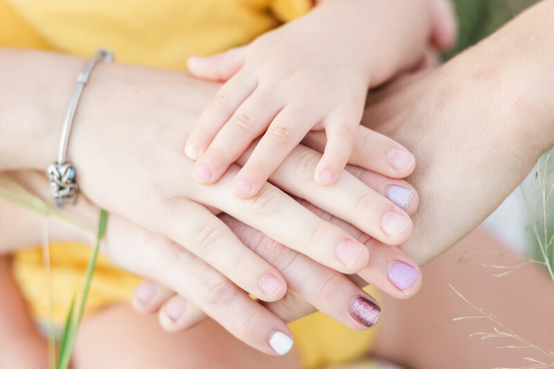 An image showing family connection - four hands stacked, holding onto each other.