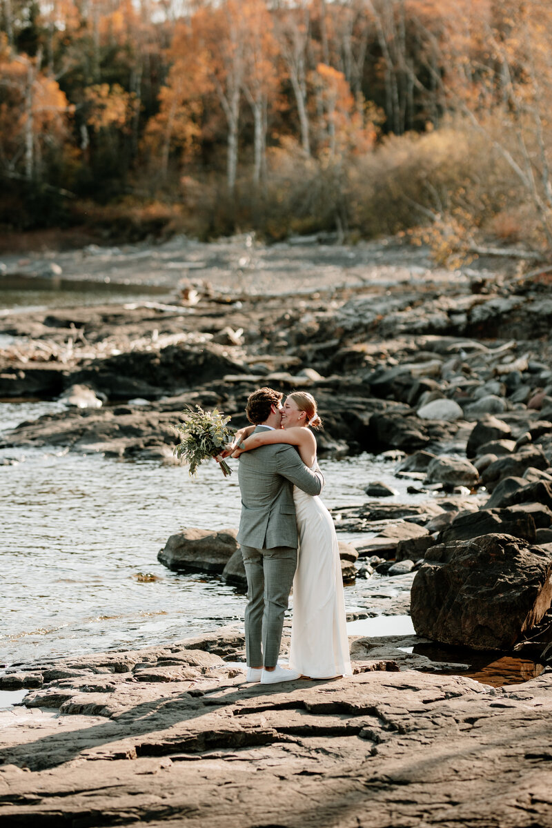 A bride and groom share a kiss along Lake Superior's North Shore following their romantic, adventurous elopement photographed by Emmie Verdell Photo.