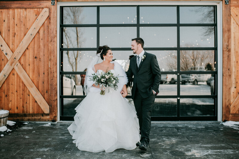 Bride taps groom on the shoulder during their first look in front of the doors at The Stables at Copper Ridge, a western iowa wedding venue. Photo by Nebraska  wedding photographer, anna brace.