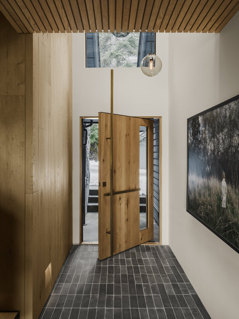 Modern cabin entry with natural stone flooring and wood siding designed by Los Angeles architect