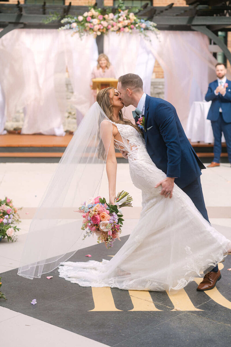 Couple is celebrating their wedding and kissing in a dipping style pose.