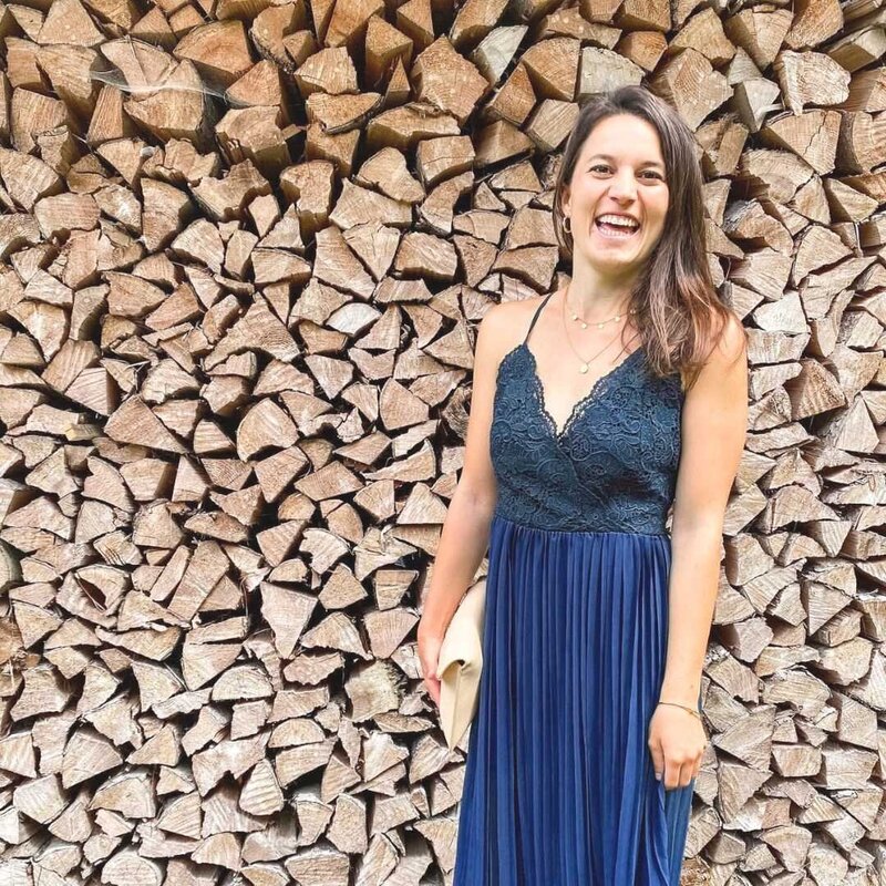 junge Frau mit braunen Haaren in blauem Sommerkleid vor einer Holzwand