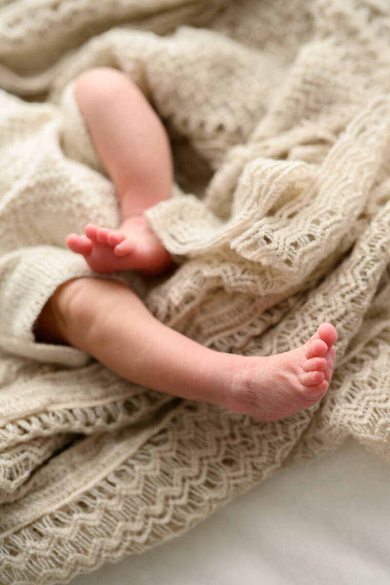 close up image of newborn baby's legs stretching out on a knit blanket, photographed in Sutherland Shire Newborn Photography studio