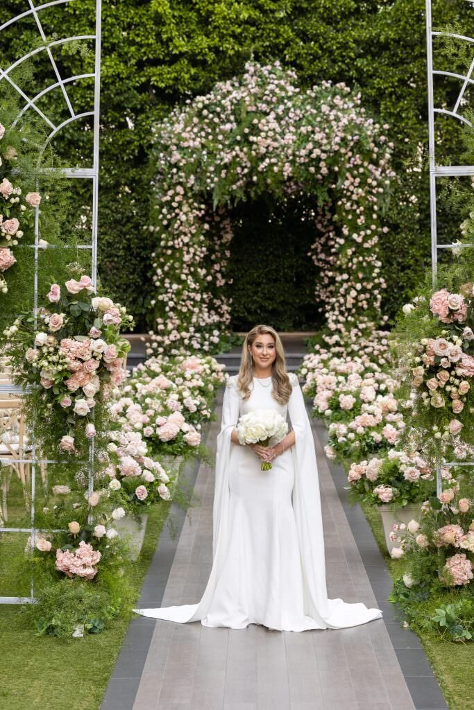 A bride standing in the middle of an aisle holding a bouquet of flowers