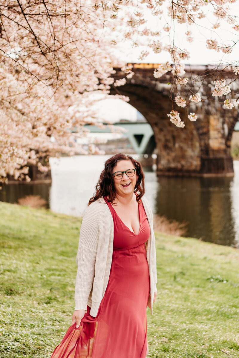 Philadelphia family photographer, Kristi, standing in front of blooming Cherry Blossom trees