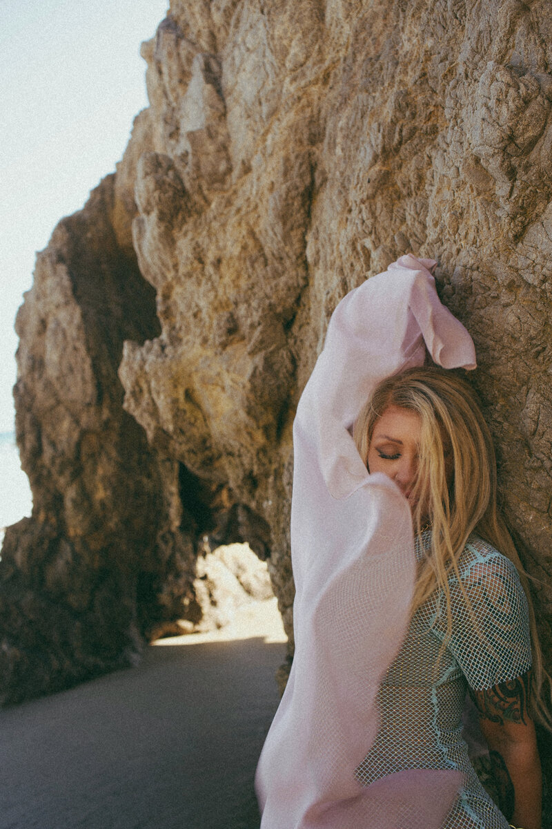 Nicky Lynn dancing on the shoreline in a blue dress, expressing freedom, joy, and emotional release