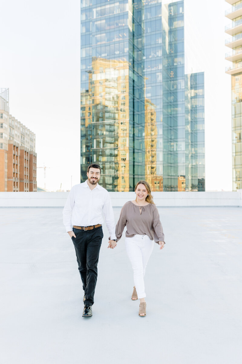 couple holding hands walking on top of parking garage