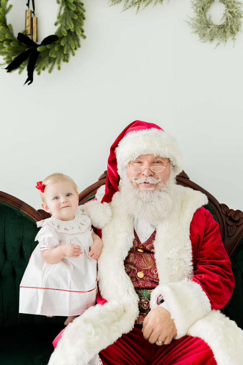 Toddler standing next to santa for santa mini session in dothan photography studio