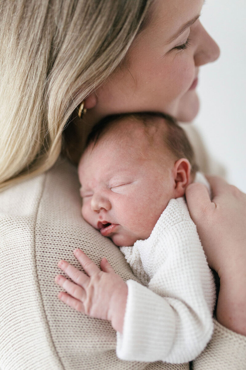 Parents look at eachother and smile whilst holding thier baby