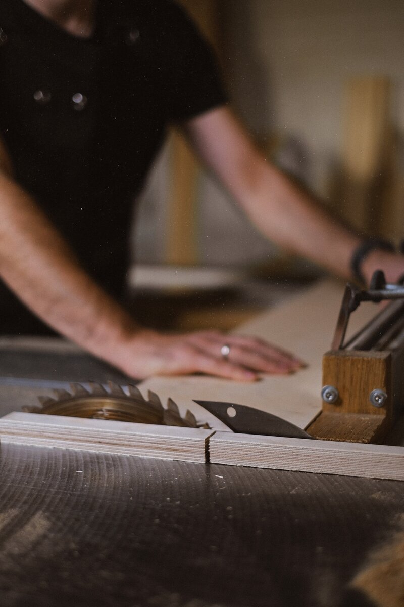 Man using a table saw to cut wood in workshop