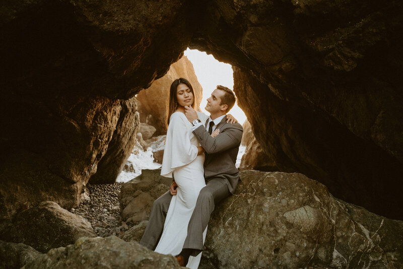 An elopement couple walks up a hill in front of a massive waterfall.