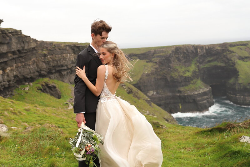 Couple embracing during  destination  elopement in ireland at the cliffs of moher