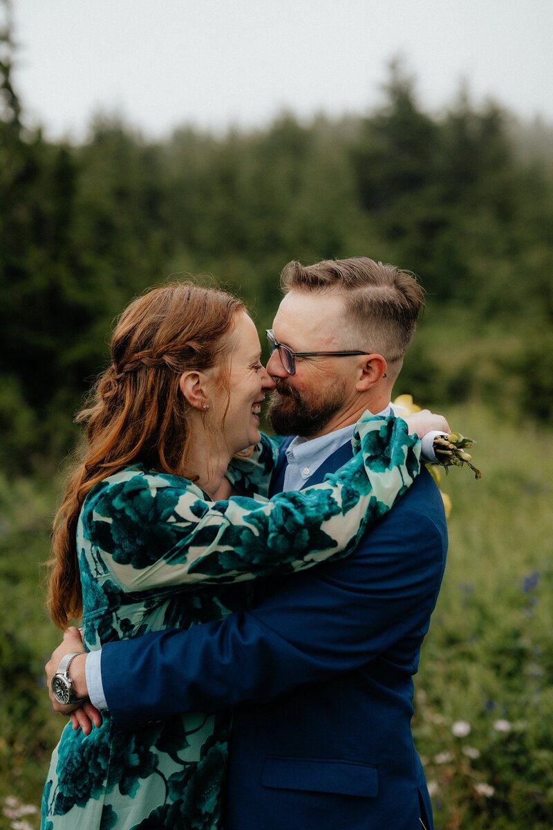 Couple embracing during an engagement photo session in Alaska with mountain views.