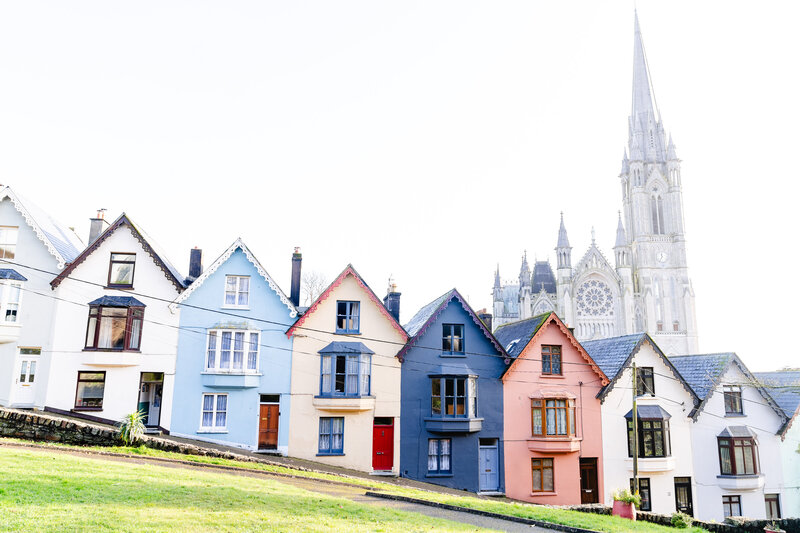 Colorful row of beautiful homes with church in the background in Cobh, Ireland