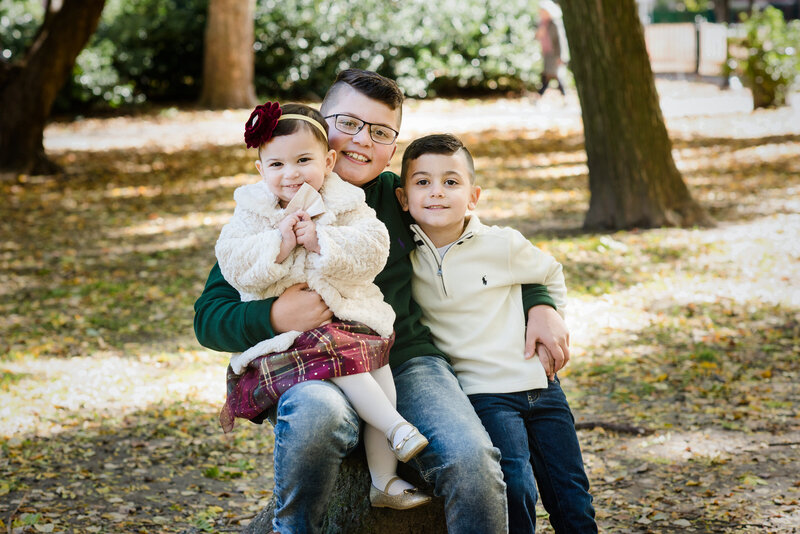 A child with his arm around one sibling and another sibling in his lap