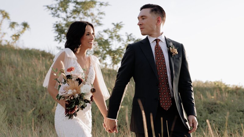 Bride and groom hold hands on the shores of Lake Michigan