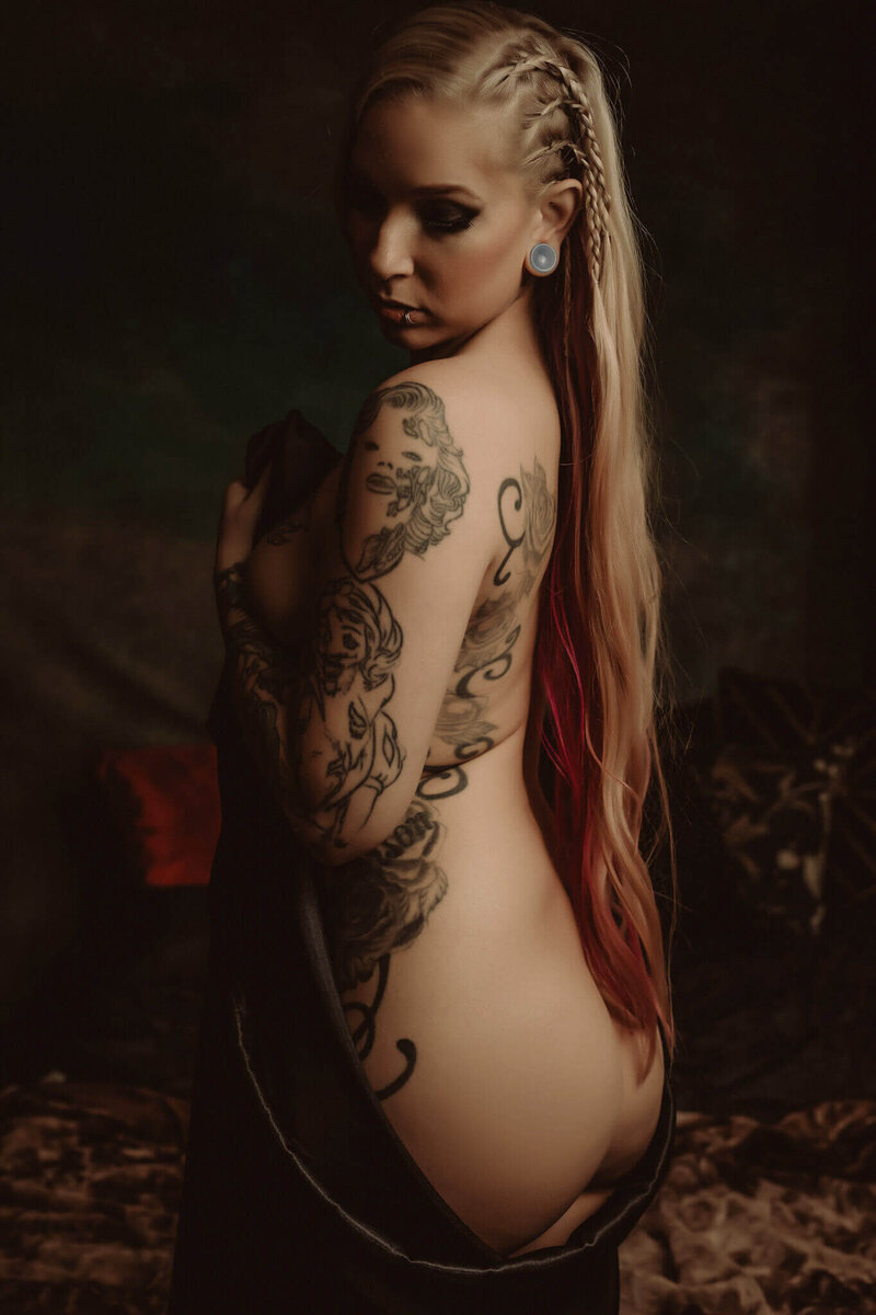 Woman with braids in her long blonde hair and tattoos standing in a boudoir studio near DFW