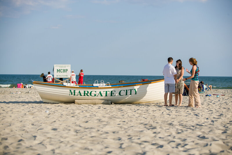 Jen Stitt guiding and posing an engaged couple on the sandy beach at the New Jersey Shore during an engagement session, creating romantic and timeless photos with a scenic coastal backdrop.