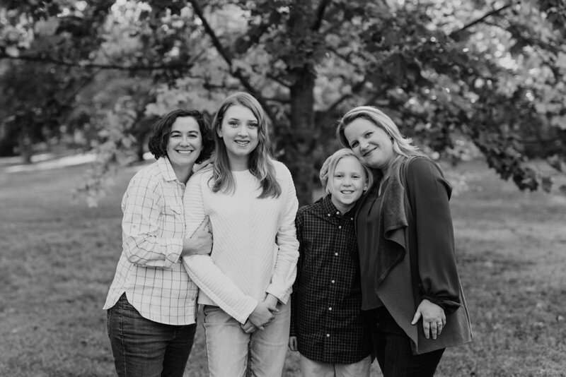 Black and white photo of two moms and son and daughter looking at camera