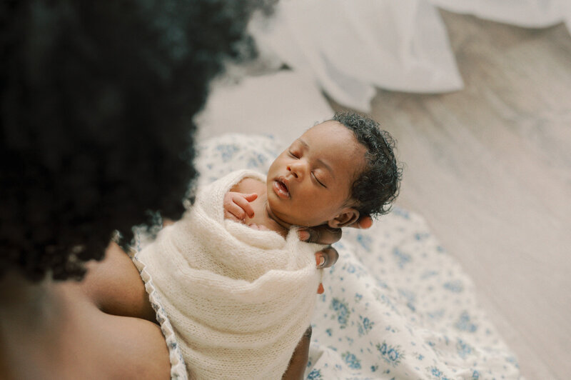 mother holding her newborn baby in a cream wrap