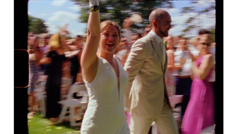 a bride holds up her flowers as she exits her wedding ceremony - a frame from a roll of Super 8 film