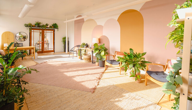 A sunny room with arched wall patterns, a table with candles, and open double doors leading to another room.